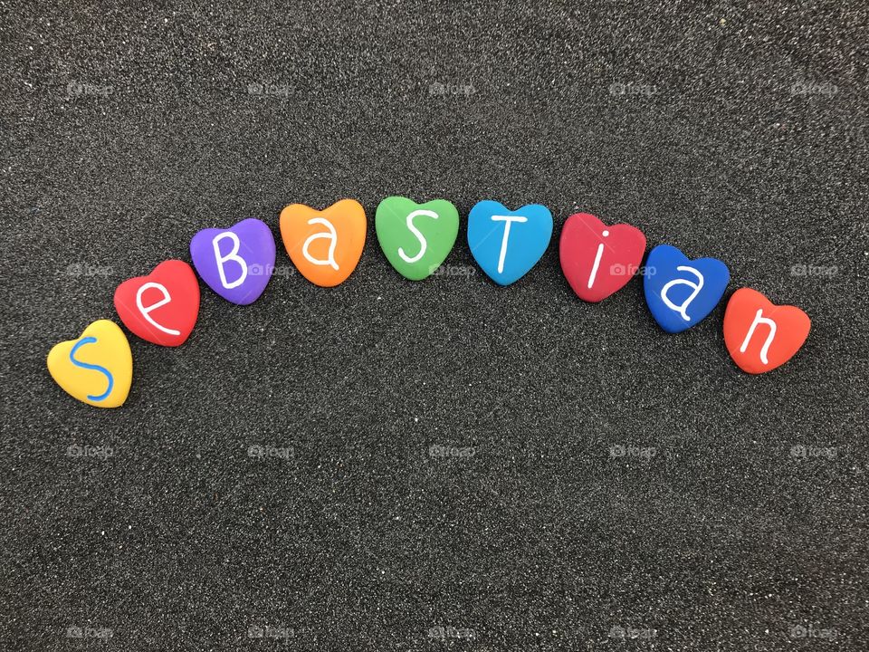 Sebastien, male given name with colored heart stones over black volcanic sand