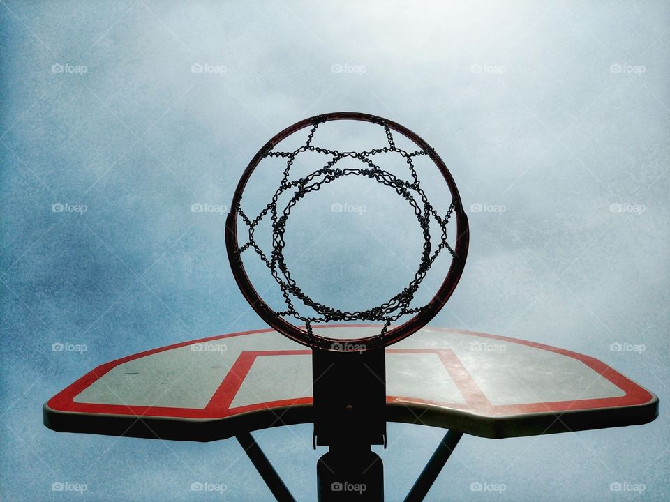 Basketball net against a cloudy blue and white sky