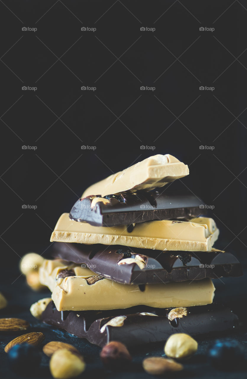 Stack of white and dark chocolate with nuts and berries.