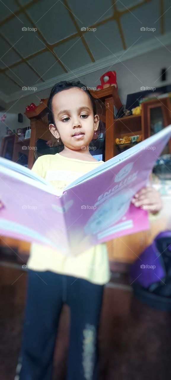 A cute girl reading a kid book very interestingly