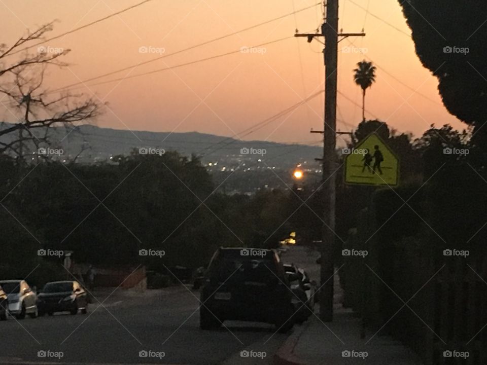 Road on a hill at sunset. The lights of a city are visible in the distance. 