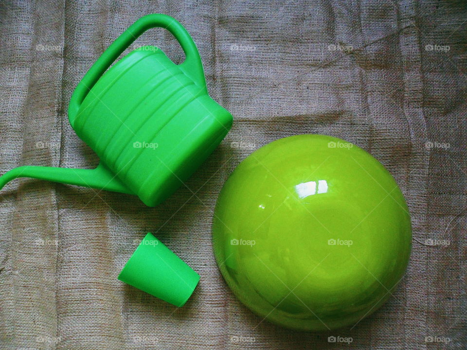 A green hemisphere, a green plastic glass and a green watering can for watering flowers