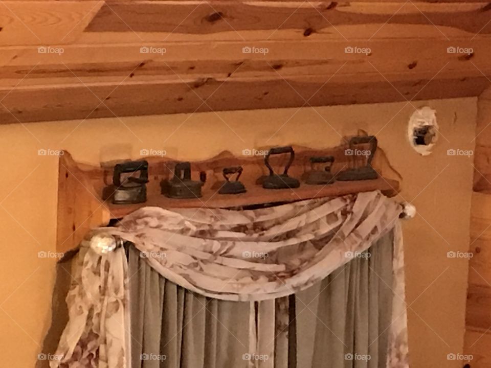 Decorating with antiques. Mini pressing irons displayed on shelf above window.