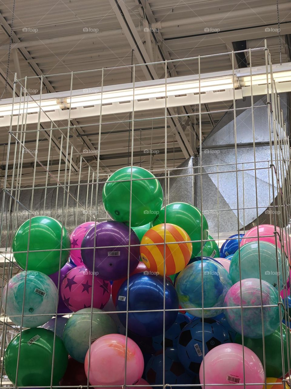 colorful stack of toy balls in a store's metal display bin