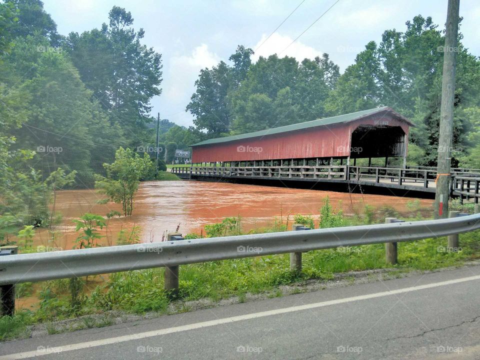 Flood waters approaching  covered bridge.
