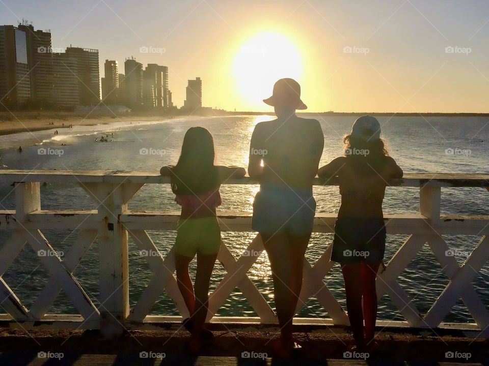 Three children admiring the sunset over the seaside bridge