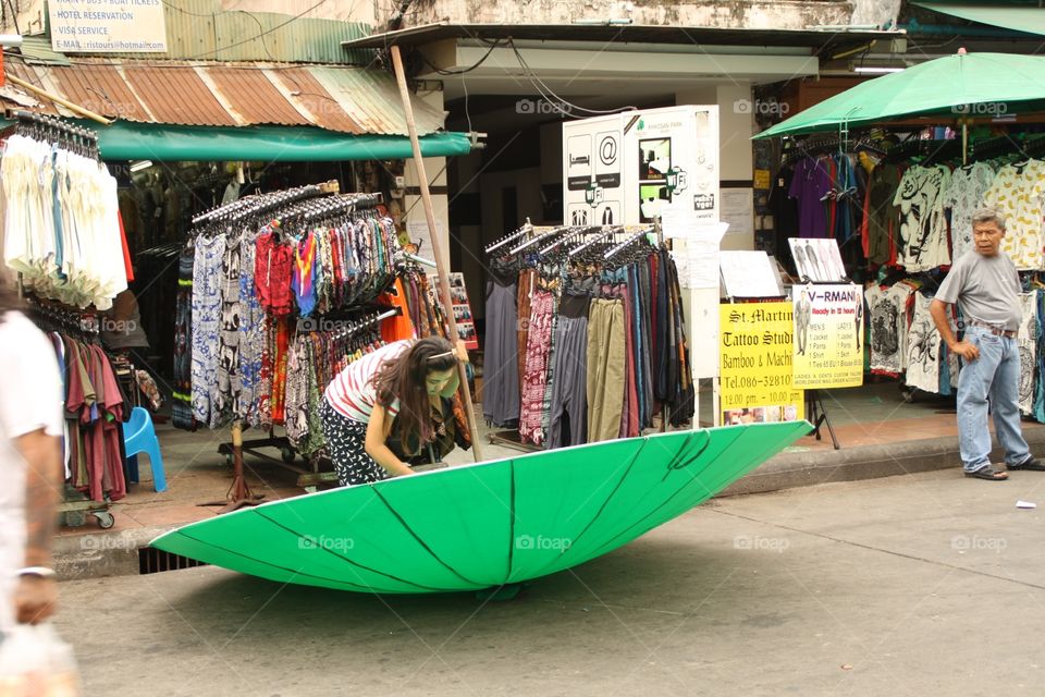 Gigant umbrella. I was walking through the market and saw this woman fighting with the gigant umbrella while the man was just looking