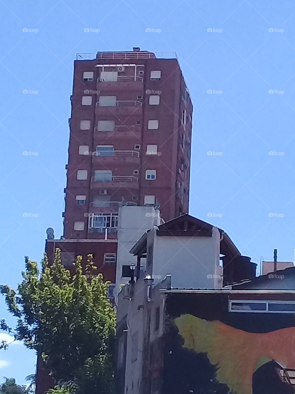 imagen de un rascacielos visto a distancia, rodeado de edificios modernos y antiguos destinados a oficinas y viviendas familiares en una céntrica avenida de la ciudad de Buenos Aires.