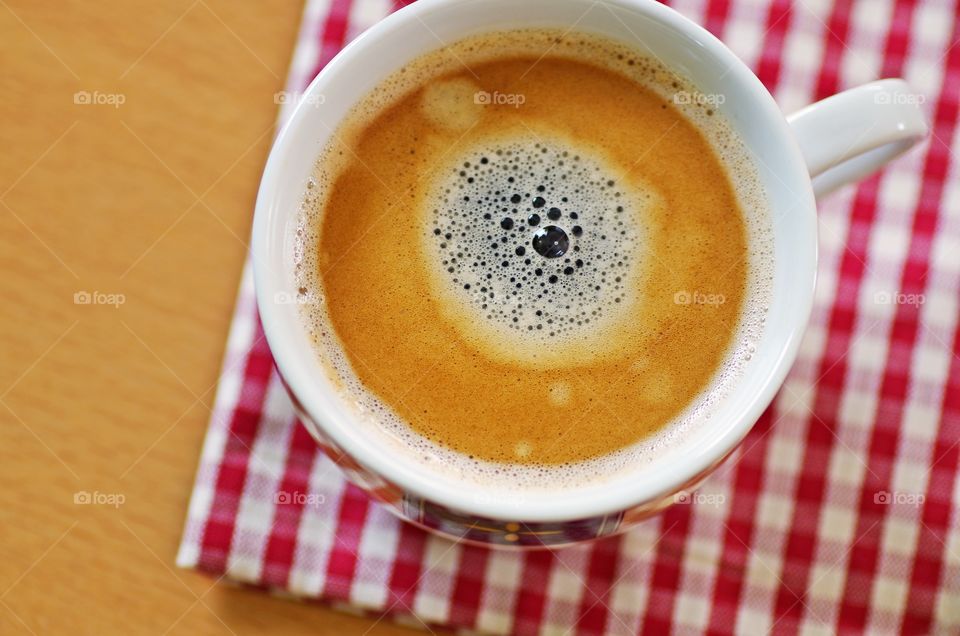 Cup of coffee on red napkin ready for breakfast.