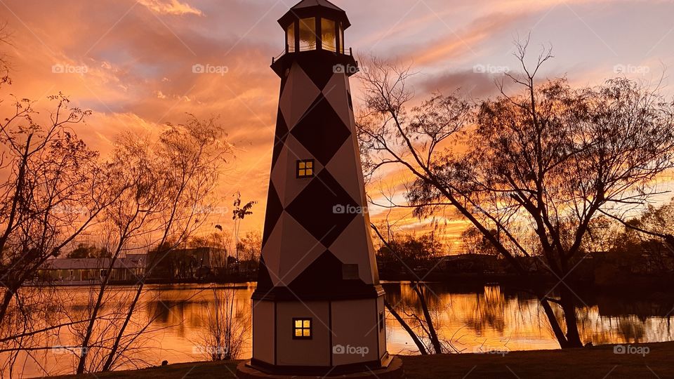 The lighthouse tonight is in very good and colorful backlit Sky full of many deep colors. Mirrored reflections on Lake Waters add Silhouettes. 