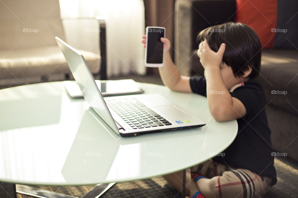 Boy frustrated with computer. Thitiwin annoyed with his phone and laptop