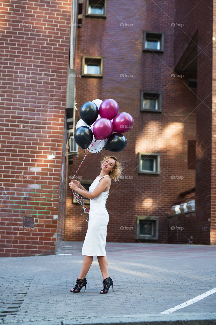 Happy sexy blond girl. Birthday girl. Girl walk at street with balloons 