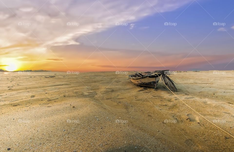 bright sunrise at the beach with an abandoned old wooden fishing boat
