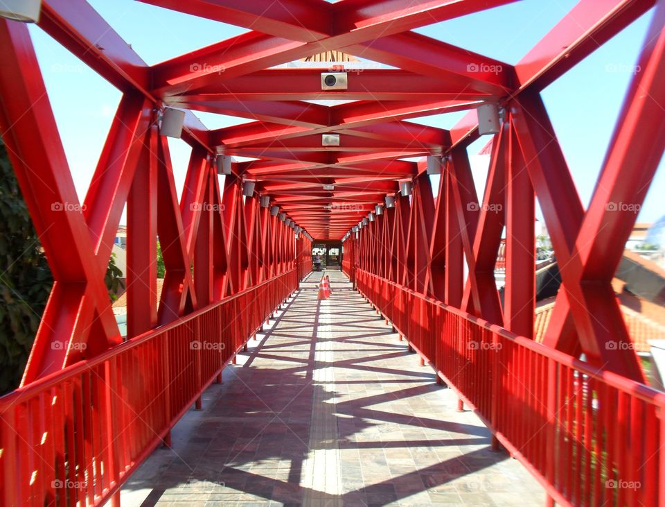 Ponte metálica vermelha com sol forte projetando sombra. 
Puente metálico rojo con sol fuerte proyectando sombra.
Red metallic bridge with strong sun casting shadow.