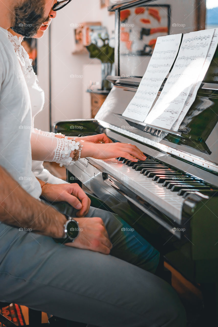 Girl teaches a pupil to play the piano