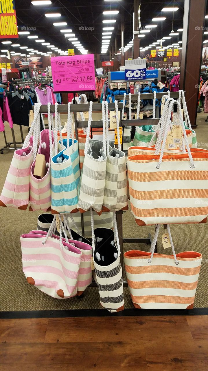 Summer beach bags hang in a store.