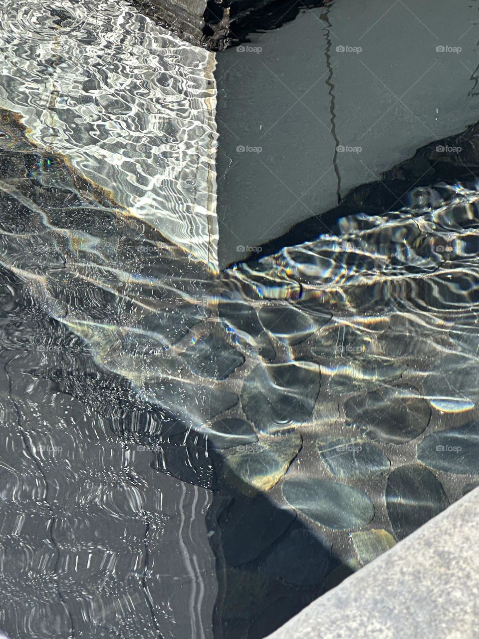 Moving water and reflections in a water wall fountain in a business district courtyard 