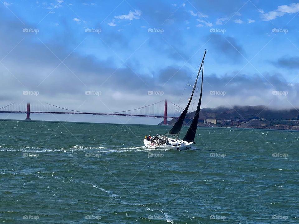 Sailboat sailing in the San Francisco Bay right in front of the Golden Gate Bridge 