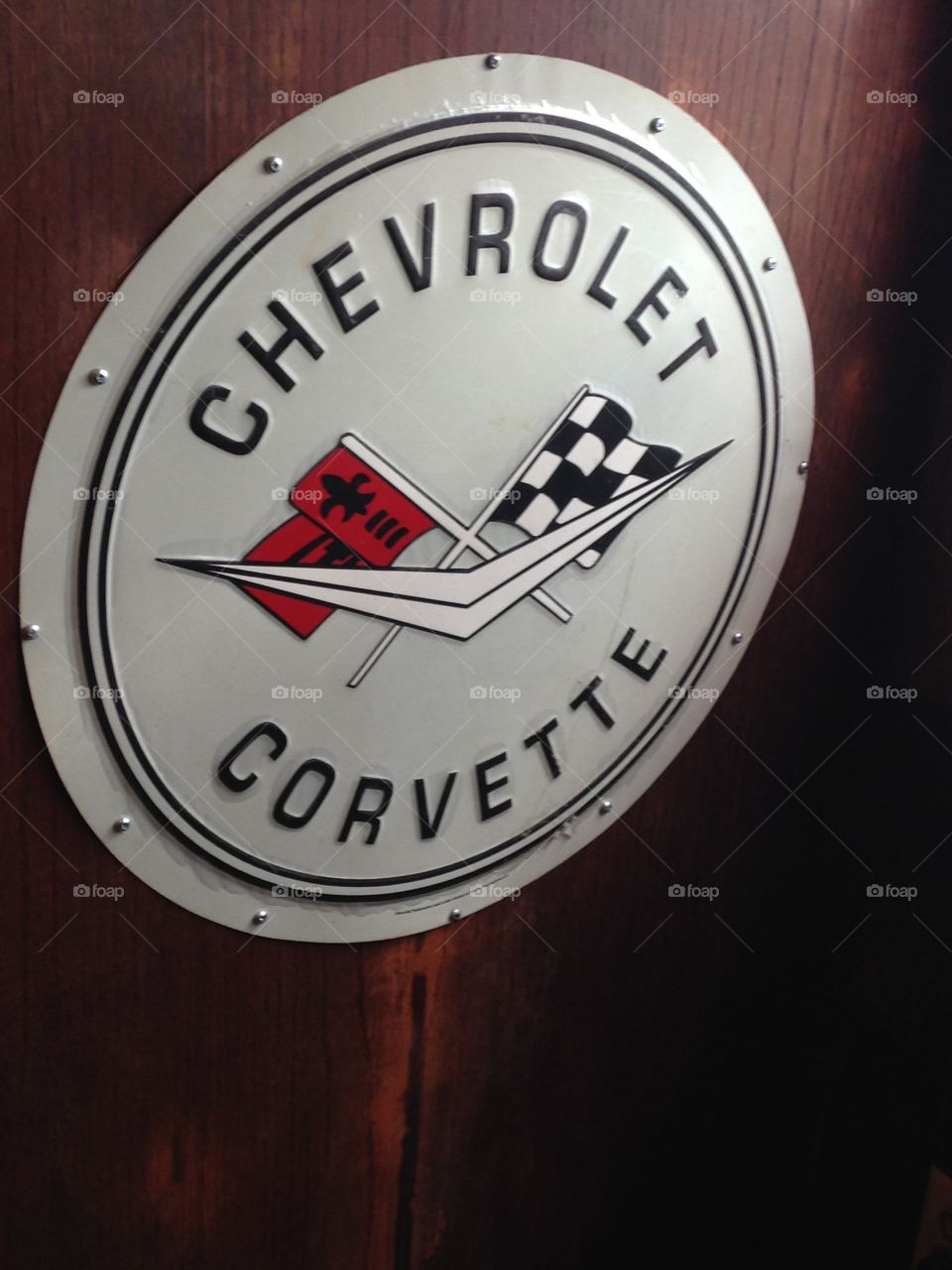 Vintage Chevrolet Corvette round metal sign on wood wall