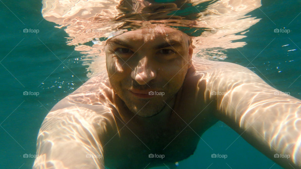 Shirtless man swimming underwater