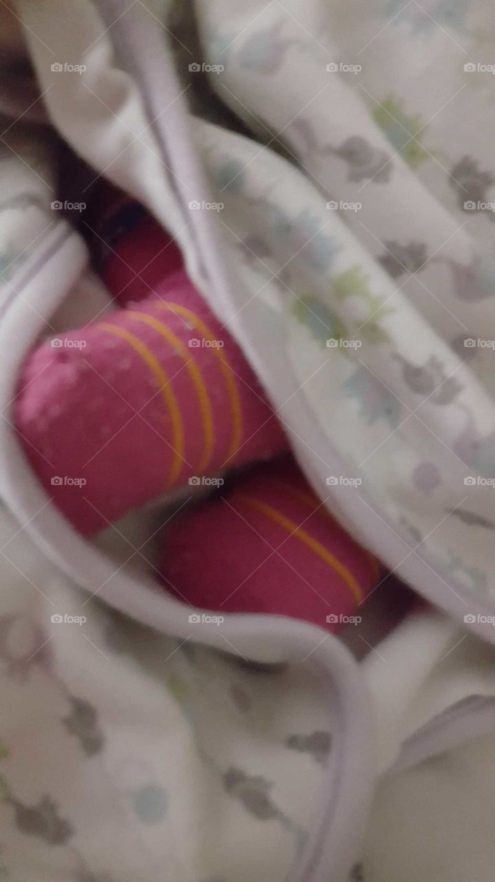 pink socked feet peak from under a swaddled blanket,  thanks to momma I'm cozy and having a great nap
