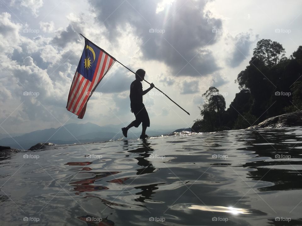 Man silhouettes holding Malaysian flag  
