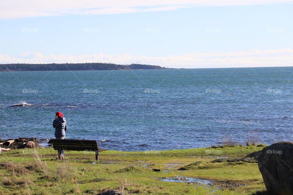 Woman by the bench facing the ocean 