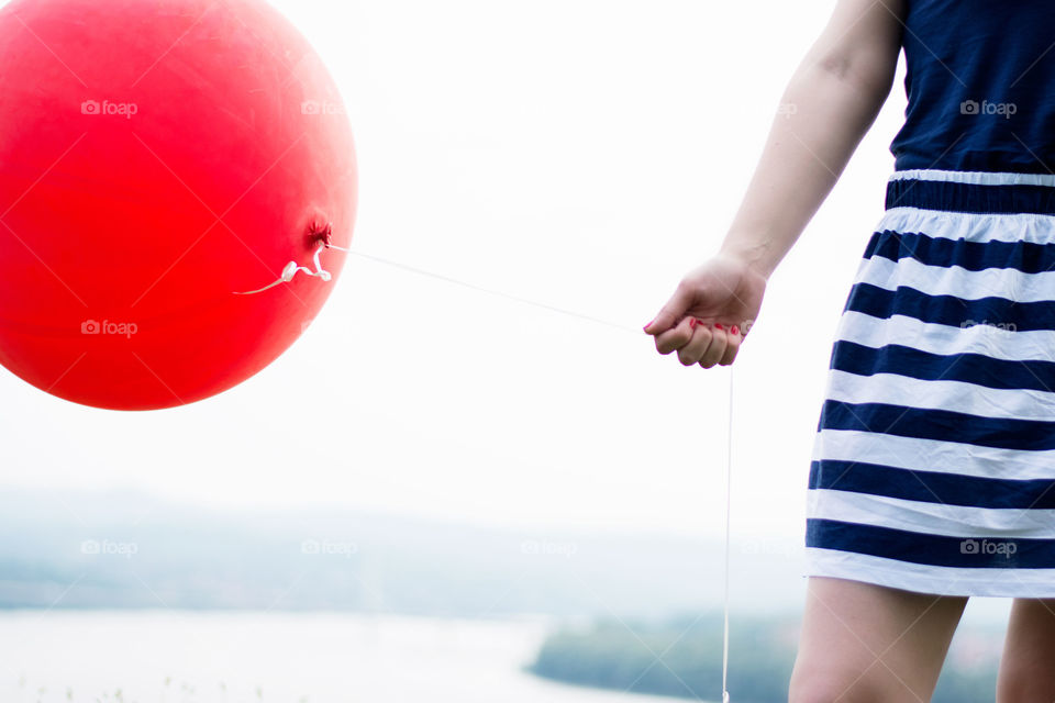 big red balloon. girl in striped skirt holding big red balloon