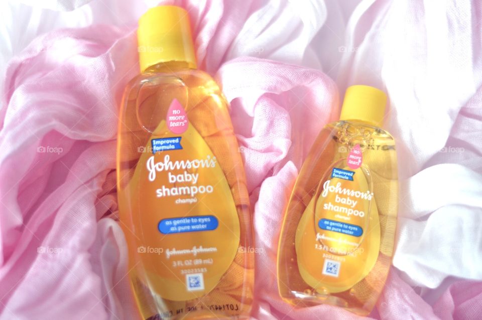 Johnson and Johnson baby shampoo on a soft pink background flat lay