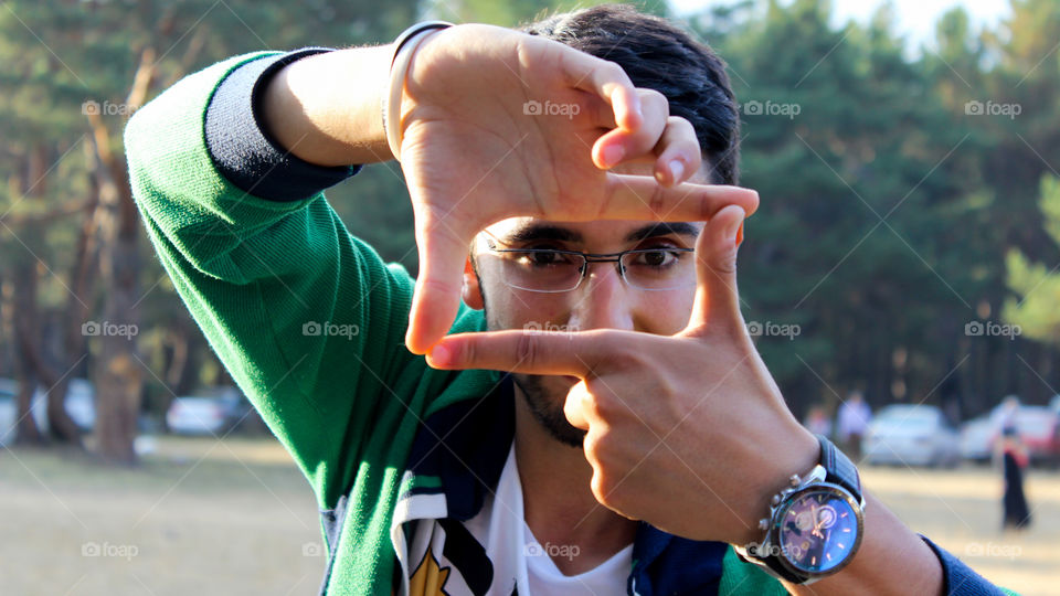 Young man showing hand frame in front of face