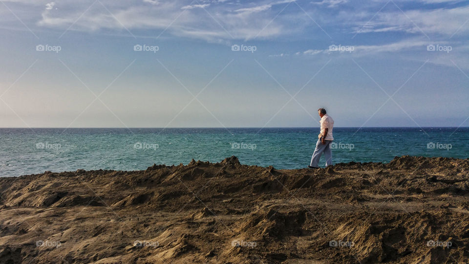 old man walking over the rocks