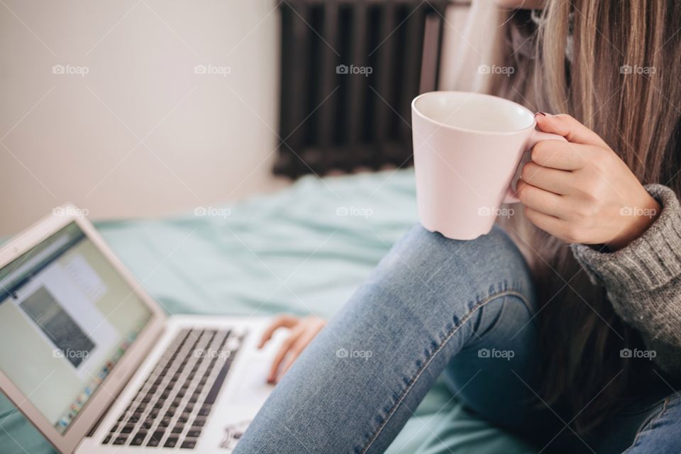 Woman drinking coffee using laptop at home
