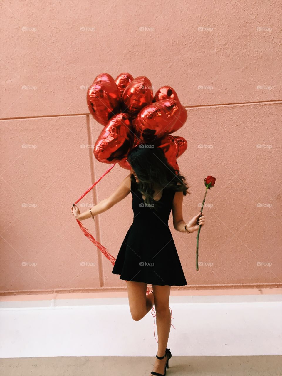 Woman holding heart shape balloons in hand