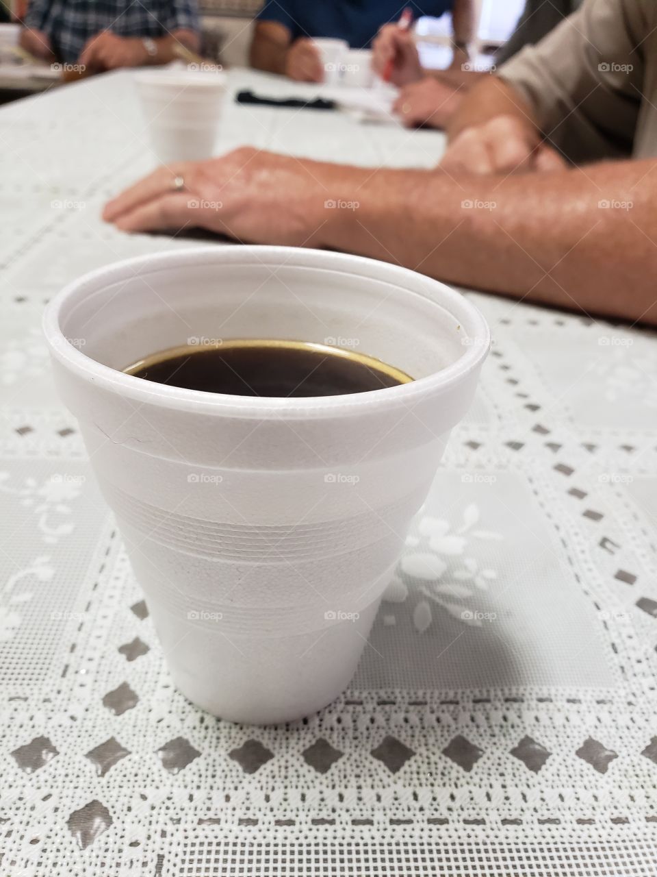 Coffee in a styrofoam Foap sitting on a table during a social gathering