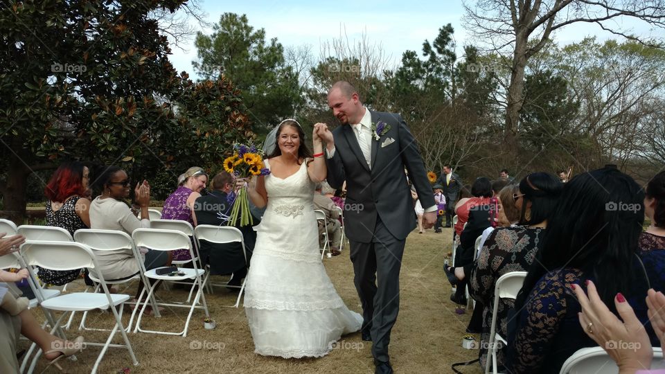 A happy bride and groom walking down the aisle after being pronounced husband and wife at an outdoor wedding