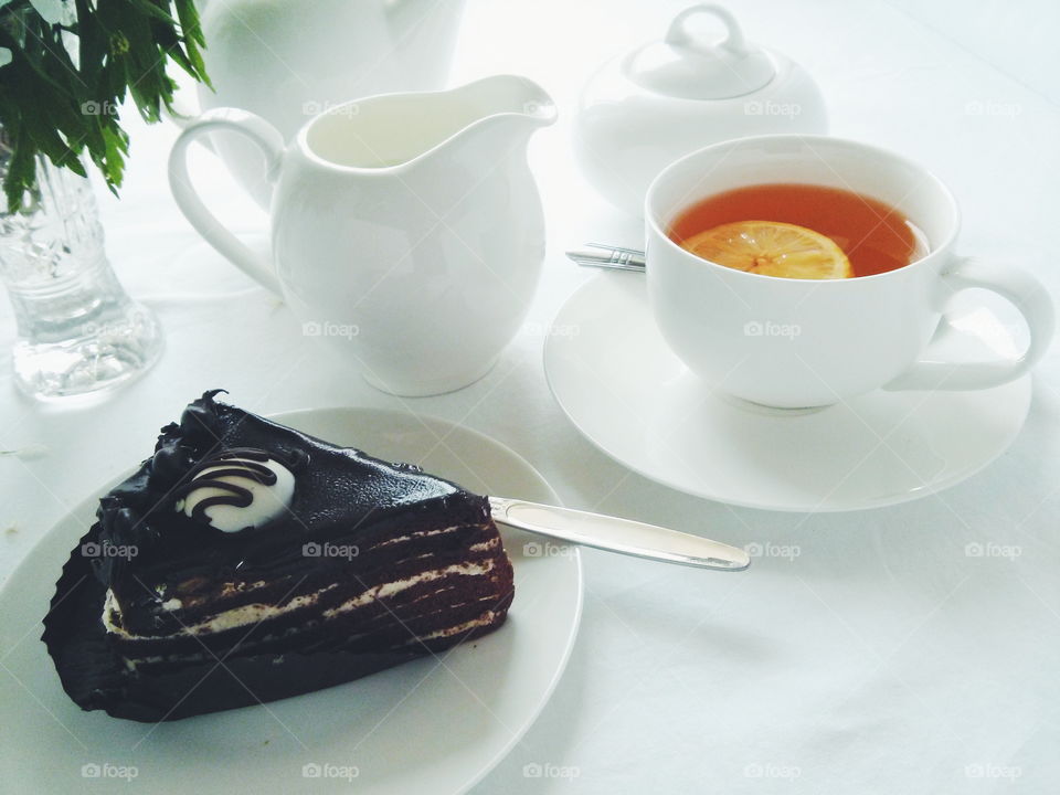 Tea time. Cup of tea with chocolate cake on white background