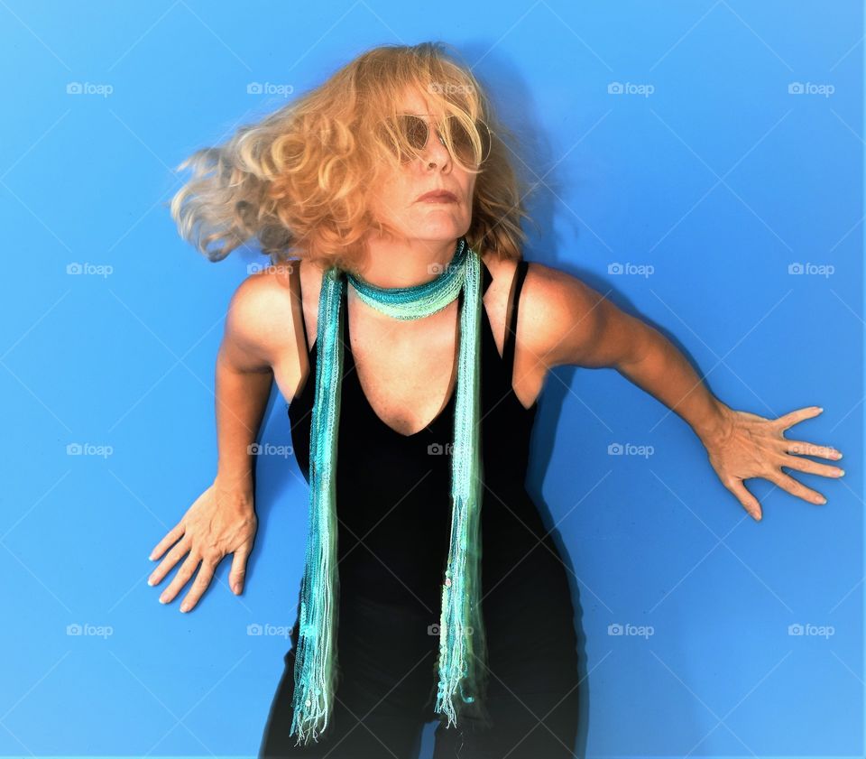 woman with waving curly hair in black suit against a blue background