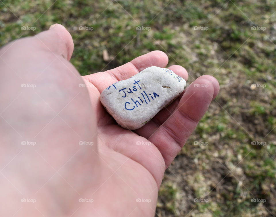 Hand holding a stone with an affirmation written on it