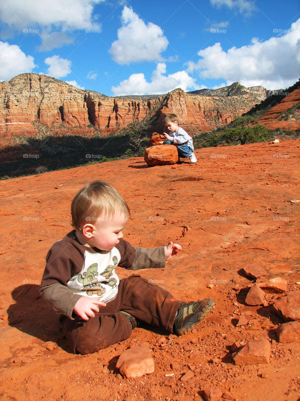 Boys Stacking Rocks in Sedona with Mountains in the Background.