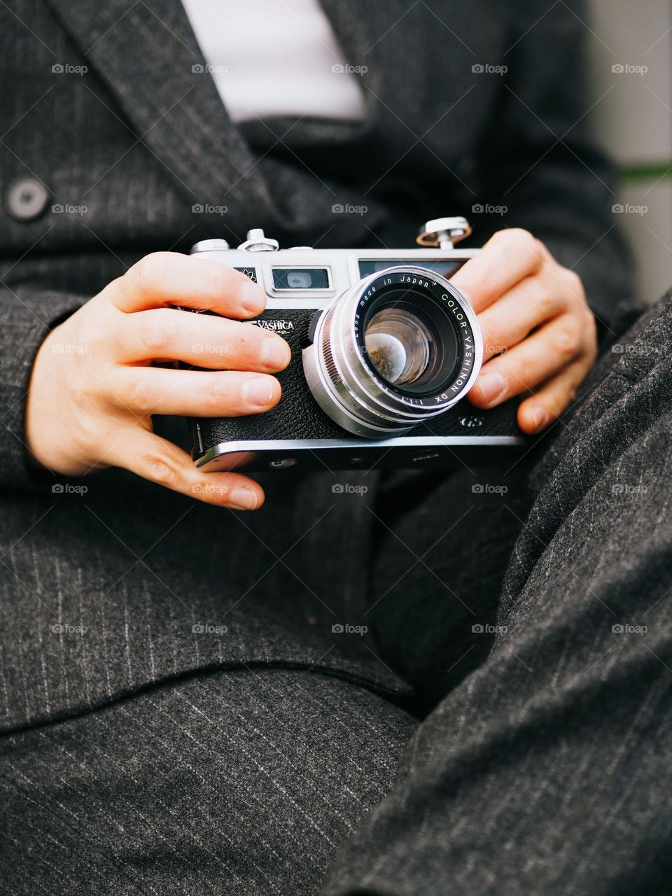 Unidentified young girl in a classic gray suit holding a film camera