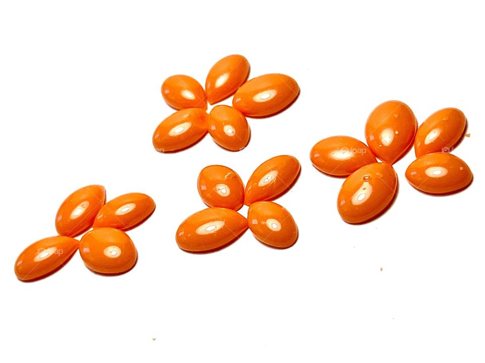 Orange wax granules for depilation on a white background. 