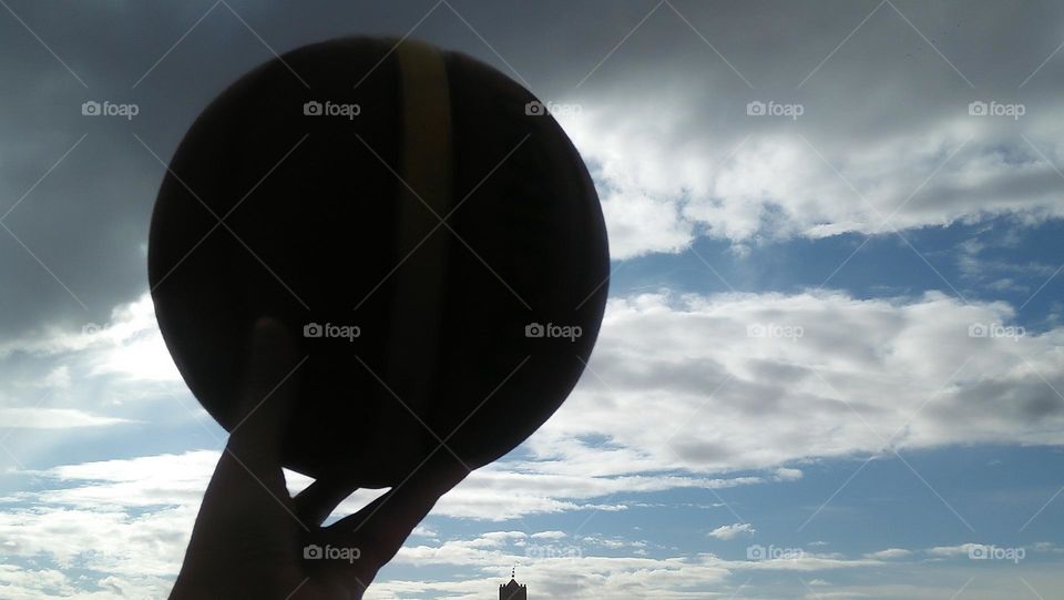 a basketball was holden high to hug dramatic sky.