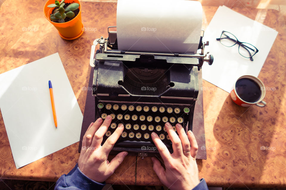 A young writer is writing his new book on his old typewriter.