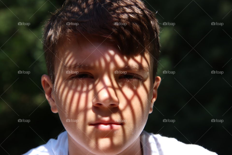 Shadows cast design on boys face on sunny day