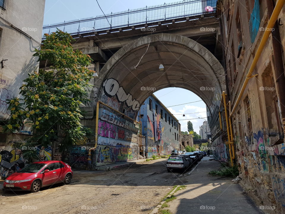 View on dilapidated street through opening under large bridge