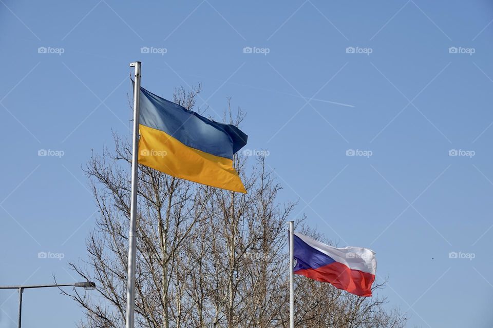 Czech and Ukrainian flags flying on poles side by side in Prague. The Czech Republic supports Ukraine.