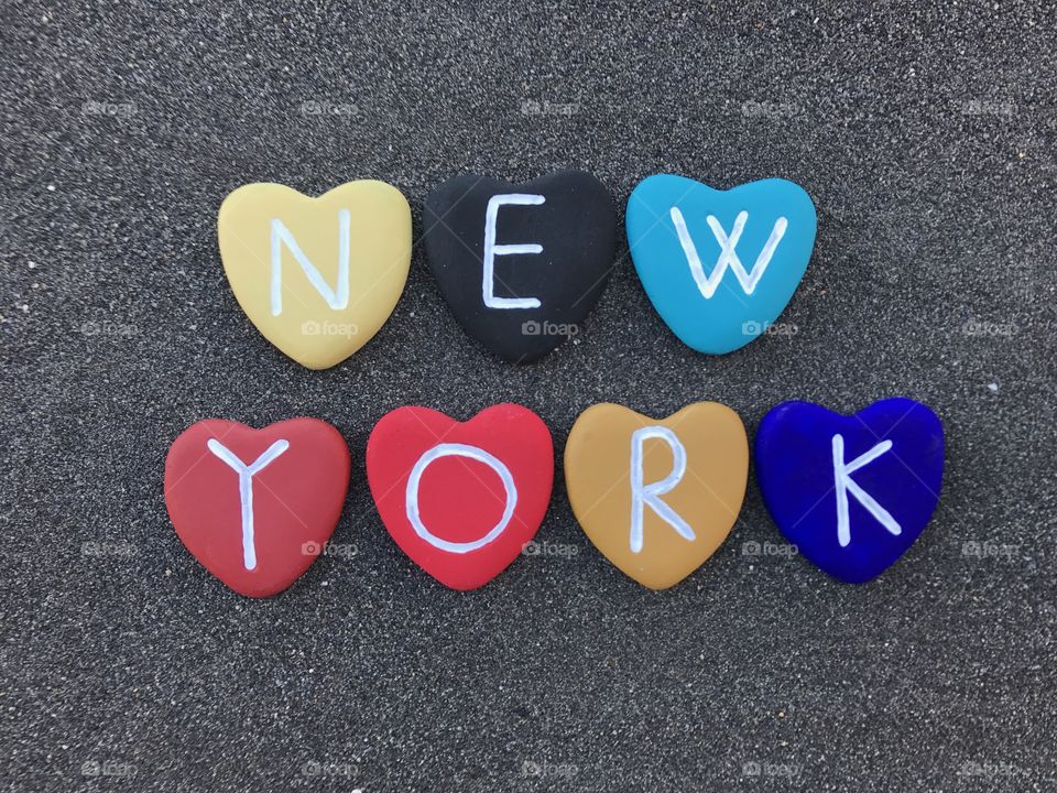 New York city name with colored stone hearts over black volcanic sand 
