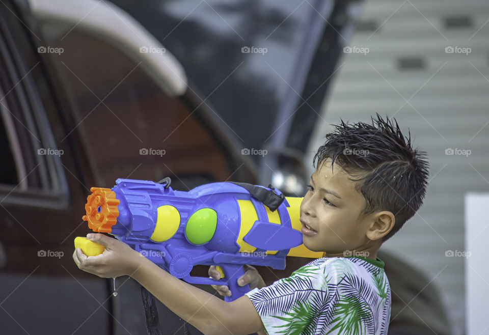 Asian boy holding a water gun play Songkran festival or Thai new year in Thailand.