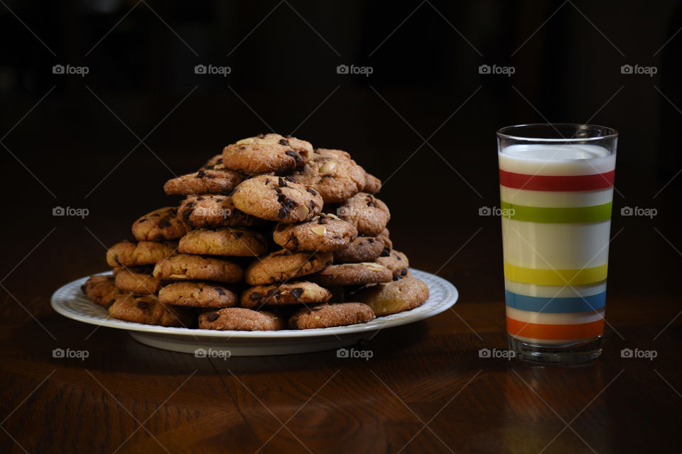 plate of cookies and a glass of milk on black background