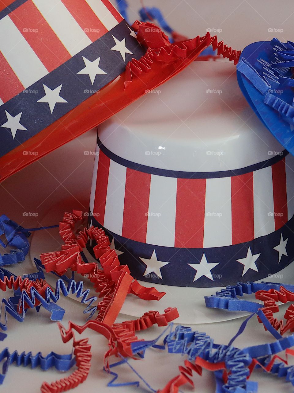 Tiny party hats in red, white, and blue with the Stars and Stripes for hat bands on a table with confetti. 